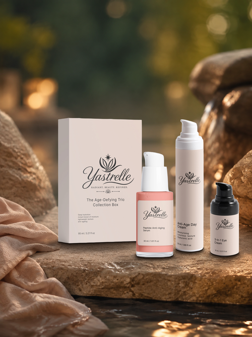 Yastrelle Age-Defying Trio Collection Box with day cream, peptide serum, and eye cream resting on a stone surface in a softly lit garden.
